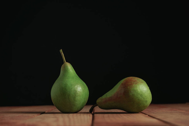 Fresh green pears on a red wooden table, beautiful black background. - Фото, зображення