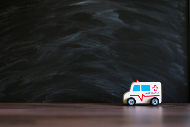 Ambulance service concept. Ambulance vehicle toy on black background with space for text - Valokuva, kuva
