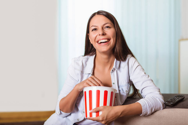 Bonita jovem sorrindo mulher assistindo a um filme e comer popcor
 - Foto, Imagem