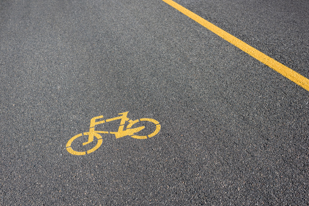 a kerékpárösvény sárga szimbóluma a szürke aszfalton  - Fotó, kép
