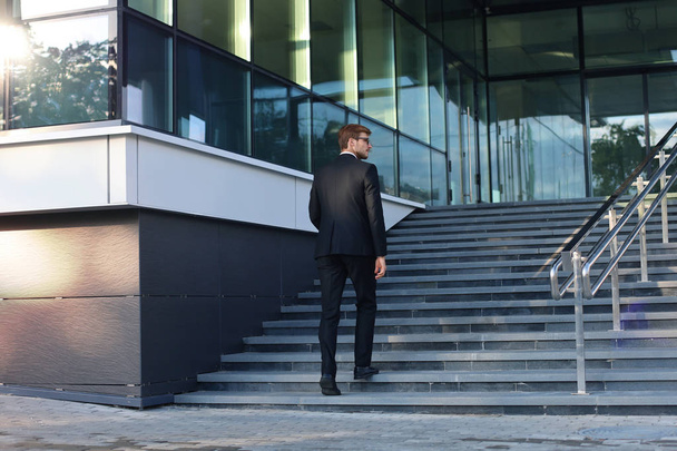Stylish successful businessman goes up the stairs of the office building. - Photo, image