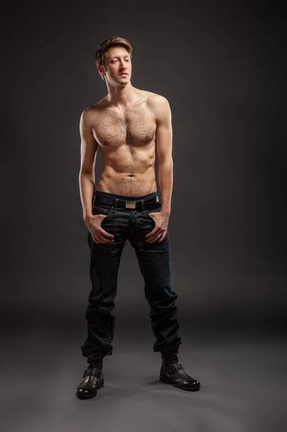 Full length portrait of a sexy young man in jeans and shirtless posing at studio. - Φωτογραφία, εικόνα