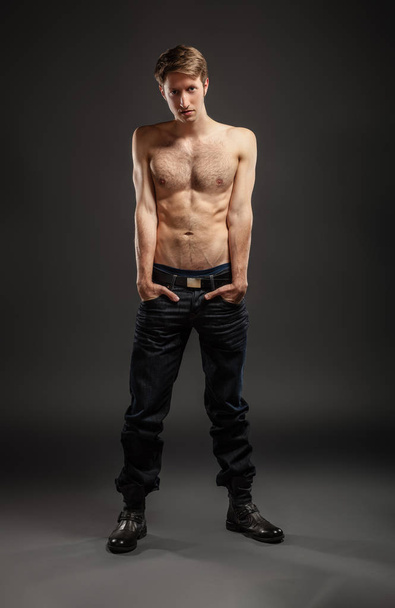 Full length portrait of a sexy young man in jeans and shirtless posing at studio. - Photo, image