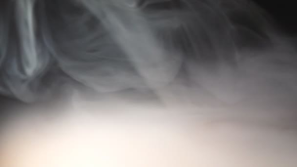 Nízký pohled na těžký bílý kouř z vopice, která se rozprostřila na povrchu stolu. Čistá Klubová pára z elektronické cigarety nebo hookahu na dřevěném stole. Černé pozadí. Zavřít - Záběry, video