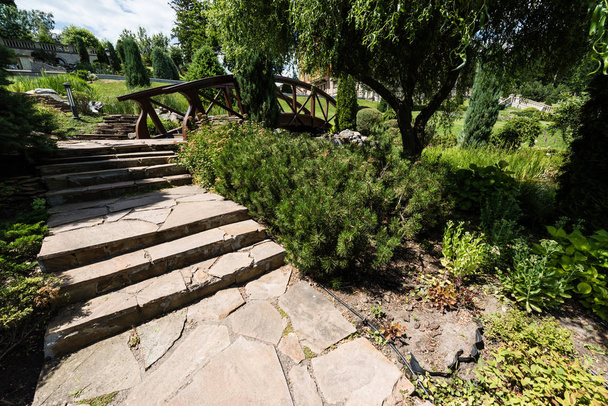 green bushes and stones near stairs and wooden bridge in park  - Photo, Image