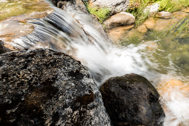 公園の草の近くの岩の上を流れる水を持つ蒸気  - 写真・画像