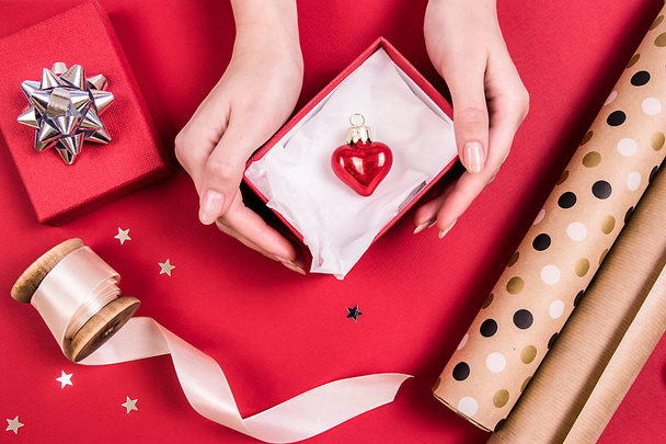 Rode glazen hart in een rode doos, beige lint, design papper. Bovenaanzicht. Holidays concept. - Foto, afbeelding