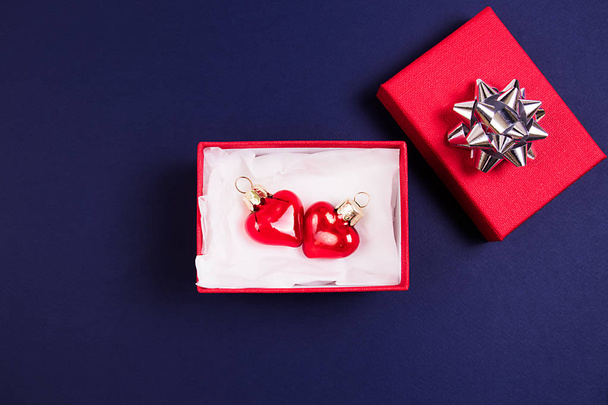 Mooie rode glazen harten in een rode doos op een donker blauwe achtergrond. Bovenaanzicht. Holidays concept. - Foto, afbeelding