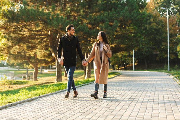 Young beautiful loving couple posing walking outdoors in park nature. - Фото, изображение