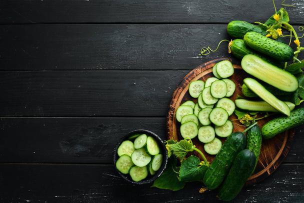 Sliced fresh green cucumbers. On a black background. Top view. Free space for your text. - Фото, зображення