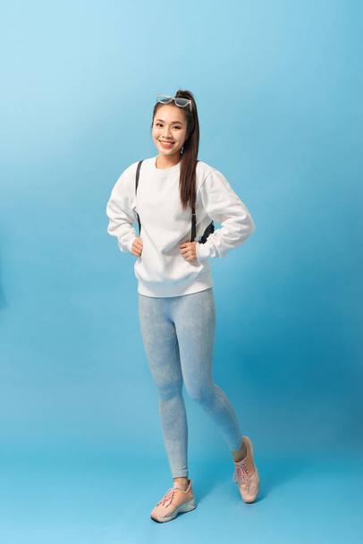 Full length photo of asian woman student walking with backpack isolated over light blue background - Foto, imagen