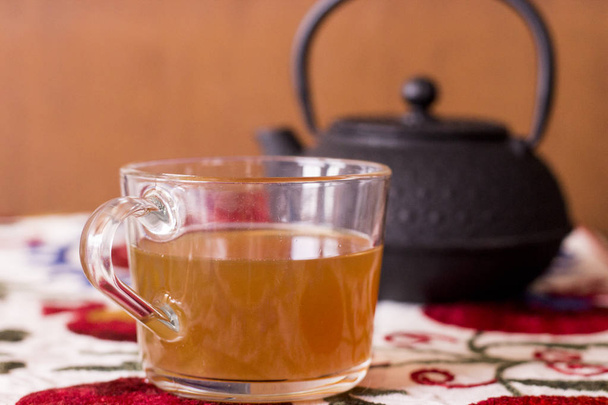 Verter el té de una tetera en una taza de té
 - Foto, imagen