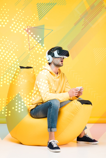 opgewonden man op boon zak stoel in virtual reality headset op geel met cyberspace illustratie - Foto, afbeelding