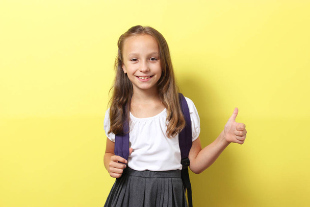 Carino sorridente studentessa con uno zaino da scuola su uno sfondo colorato. Torna al concetto di scuola - Foto, immagini