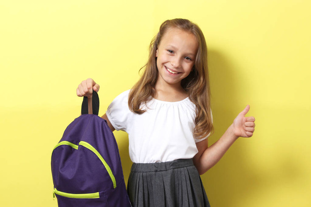 Cute uśmiechnięta uczennica ze szkolnym plecakiem na kolorowym tle. Powrót do koncepcji szkoły - Zdjęcie, obraz