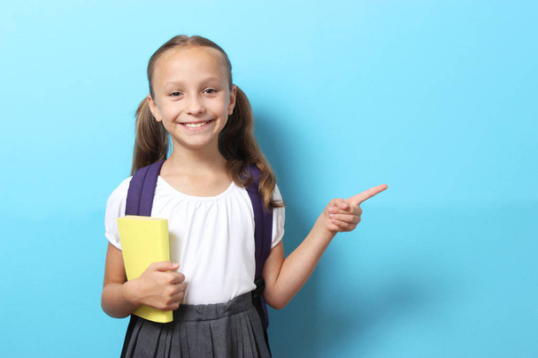 Quita chica de escuela sonriente con una mochila de la escuela en un fondo coloreado. Volviendo al concepto de escuela - Foto, imagen