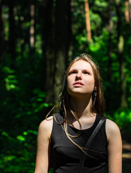 Outdoor portrait of young teenager brunette girl with long hair looking up in forest - Foto, imagen