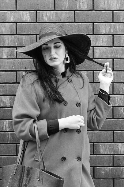Modeporträt von Glamour sinnliche junge stilvolle Dame. Frau mit schwarzem Hut, rotem Mantel und Tragetasche. - Foto, Bild