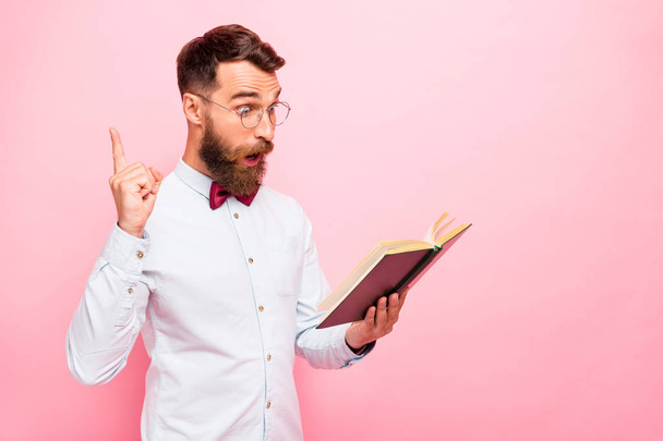 Photo of thoughtful intellectual person holding opened paper literature in hands pointing fore-finger up isolated pastel background - Foto, afbeelding