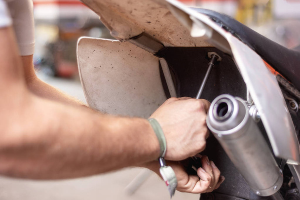 Motorbike mechanic repairing an exhaust pipe system at garage. - Фото, изображение