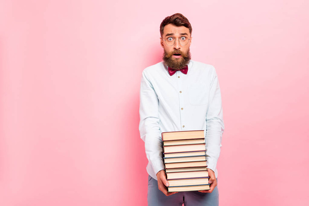 Photo of frustrated astonished saying omg person holding great pile of books in hands wearing white shirt isolated pastel background - Zdjęcie, obraz