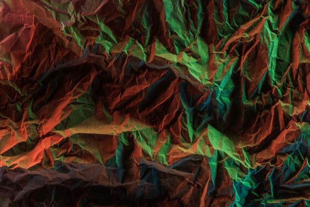 top view of crumpled paper with green colorful lighting in darkness - Photo, Image