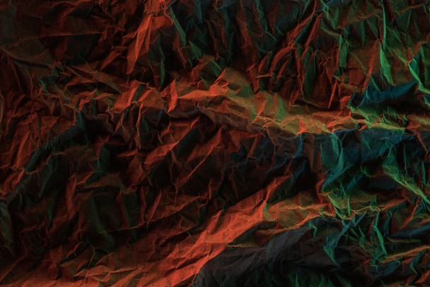 top view of crumpled paper with colorful lighting in darkness - Фото, зображення