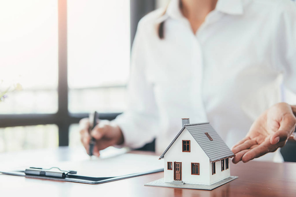 Модель дома с агентом по недвижимости и клиентом обсуждают контракт на покупку дома
 - Фото, изображение