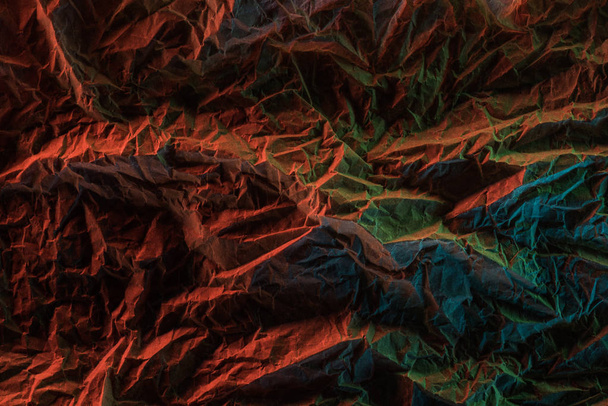 top view of crumpled paper with colorful lighting in dark - Fotó, kép