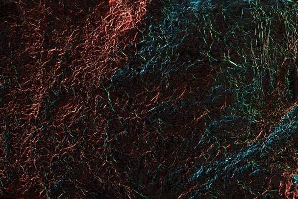 αφηρημένο φόντο γυαλιστερό τσαλακωμένο αλουμινόχαρτο με πολύχρωμο φωτισμό - Φωτογραφία, εικόνα