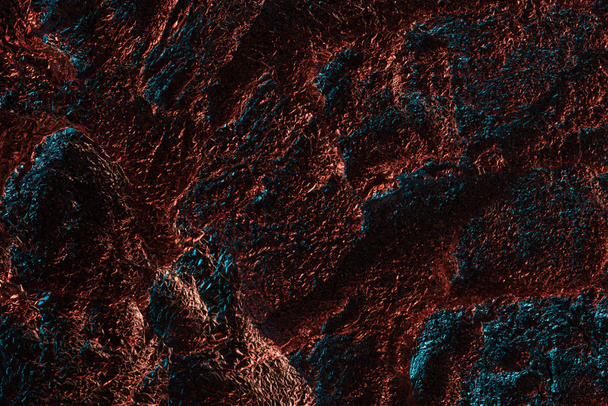 Κορυφαία όψη του γυαλιστερού τσαλακωμένο αλουμινόχαρτο με πολύχρωμη αντανάκλαση φωτισμού στο σκοτάδι - Φωτογραφία, εικόνα