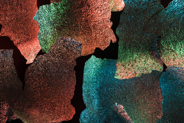 abstract background of ragged foil with colorful illumination isolated on black - Foto, imagen