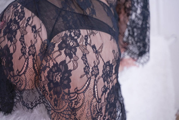 charming plus size caucasian woman dressed in a beautiful lace black lingerie and a sheer robe. curvaceous young girl in fashion underwear at home alone. - Fotografie, Obrázek
