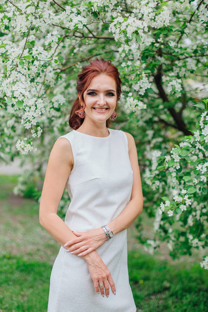 Charming woman wearing beautiful white dress under the apple tree - Fotografie, Obrázek