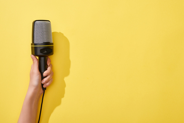 vista cortada da mulher segurando microfone no fundo amarelo
  - Foto, Imagem