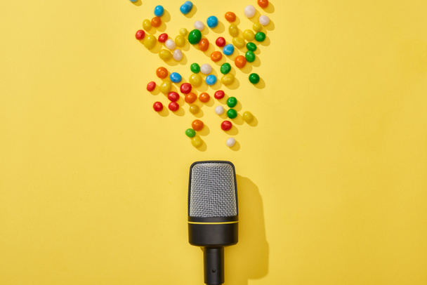 top view of microphone and candies on bright and colorful background  - Fotó, kép