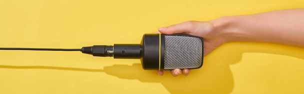 panoramic shot of woman holding microphone on yellow background  - Fotoğraf, Görsel