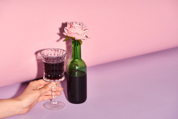 cropped view of woman holding glass with wine on colorful background  - Фото, зображення