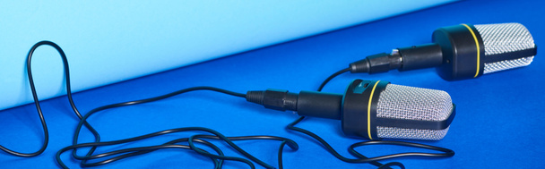 Panoramaaufnahme schwarzer Mikrofone mit Drähten auf buntem Hintergrund  - Foto, Bild