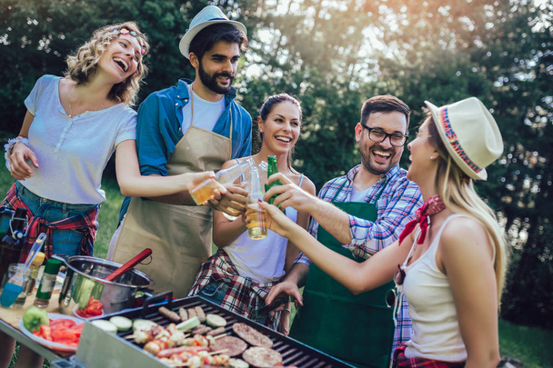 Jonge vrienden met plezier grillen vlees genieten van barbecuefeest. - Foto, afbeelding