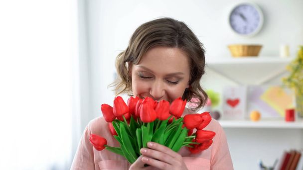 Beautiful woman sniffing red tulips, present from boyfriend, holiday celebration - Fotografie, Obrázek