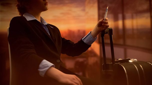 Stewardess holding tickets, waiting for flight at airport, sunset background - Zdjęcie, obraz