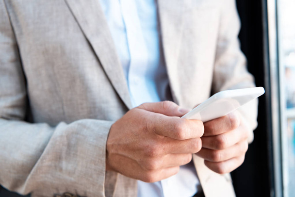 обрезанный вид бизнесмена в формальной одежде, держащего смартфон
 - Фото, изображение