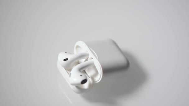 Білі бездротові навушники з футляр для заряджання знаходяться на білому фоні. Макрос. - Кадри, відео