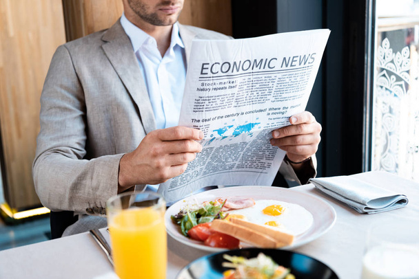 businessman sitting at served table and reading newspaper in cafe - Photo, Image