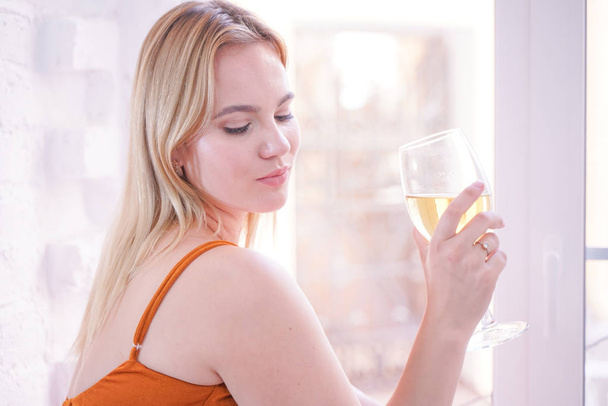 pretty plus size caucasian woman drink wine in the morning alone at home on white fur windowsill  - Photo, image