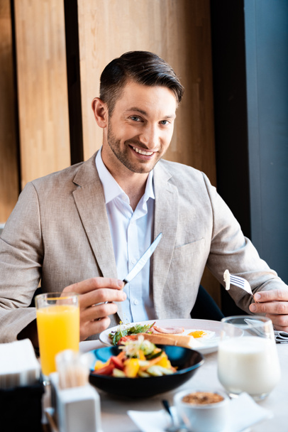 smiling businessman looking at camera while eating in cafe - Foto, Imagem