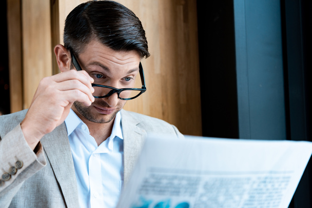surprised businessman in glasses reading newspaper in cafe - Фото, изображение