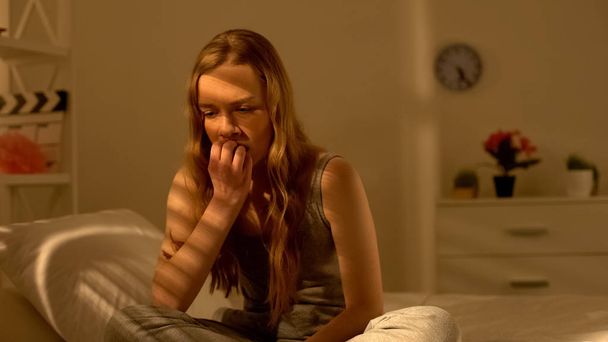 Anxious young woman sitting in bedroom thinking of problem, suffering stress - Фото, зображення