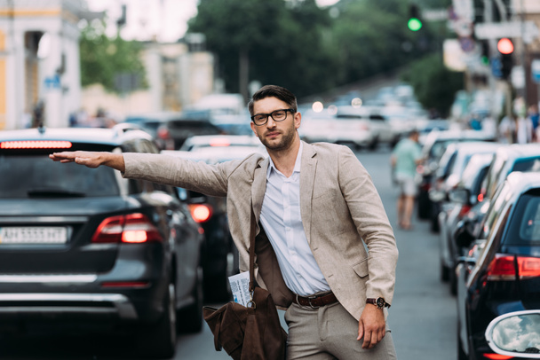 uomo d'affari in occhiali con borsa cavalcare autostop sulla strada
 - Foto, immagini